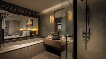 Une salle de bain moderne avec un grand miroir, une baignoire, une douche et un meuble-lavabo.