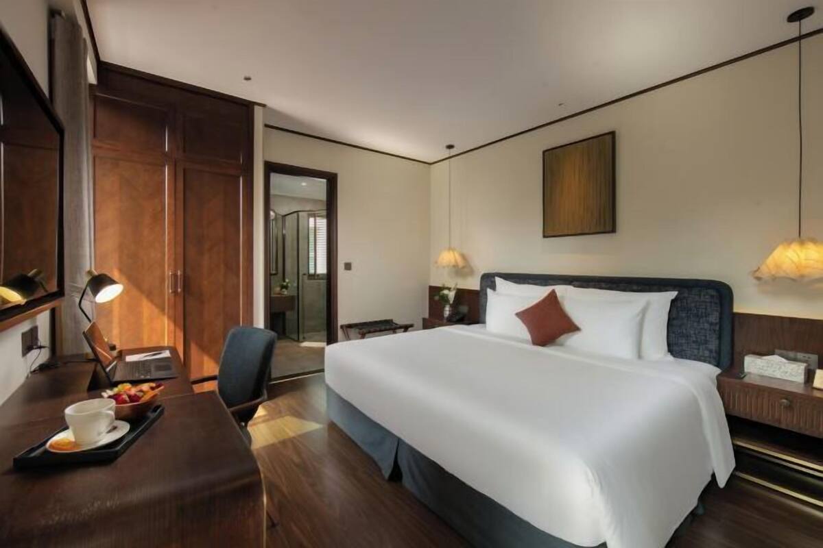 Hotelkamer met een groot bed, een bureau met lamp, een stoel en een eettafel met een dienblad eten.