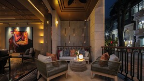 Un'area lounge moderna con mobili in vimini, un tavolo rotondo al centro e un grande quadro astratto appeso alla parete.