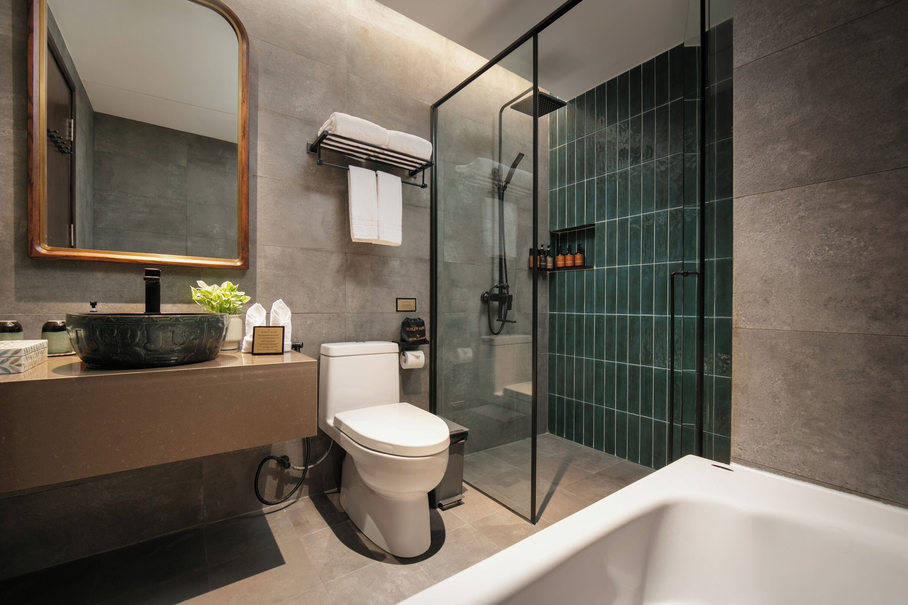 Une salle de bain moderne avec une douche à parois de verre, des toilettes blanches, un grand miroir et une baignoire.