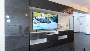 A modern living room with a flat-screen TV mounted on a dark wood cabinet, a framed picture, and a white rug. - Stylish Retreat: 1-Bed, Pool, Sleeps 3 REF001 (Benalmádena)