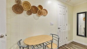 A hallway with a round table and chairs, a white door, and a wall-mounted mirror.