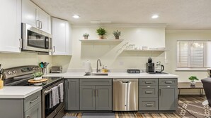 A modern kitchen with grey cabinets, a stainless steel dishwasher, and a built-in microwave.