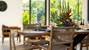 A dining area with a round wooden table, wicker chairs, and a floral centerpiece. - Private Pool • Outdoor Showers • Near Beaches (Uluwatu)