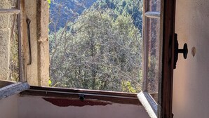 Ein Zimmer mit Fensterblick auf eine gebirgige Landschaft.