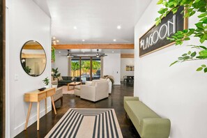 A spacious living area with a pool, a green sofa, a wooden console table, and a large mirror.