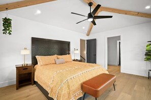 A bedroom with a bed, bedside table, lamp, ceiling fan, and a hanging plant. - Private Lagoon Pool and Jacuzzi & Theater! (Princeville)