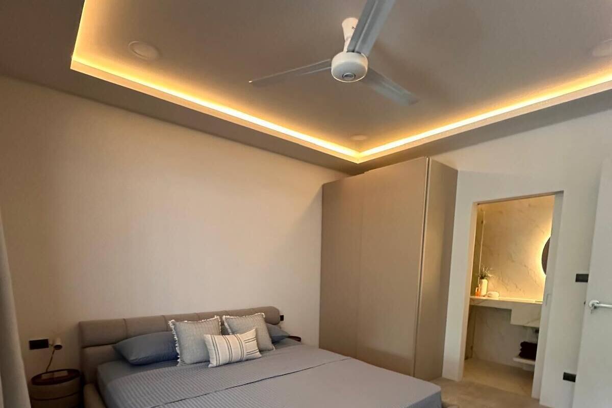 Un dormitorio moderno con una cama grande, ventilador de techo y armario empotrado.