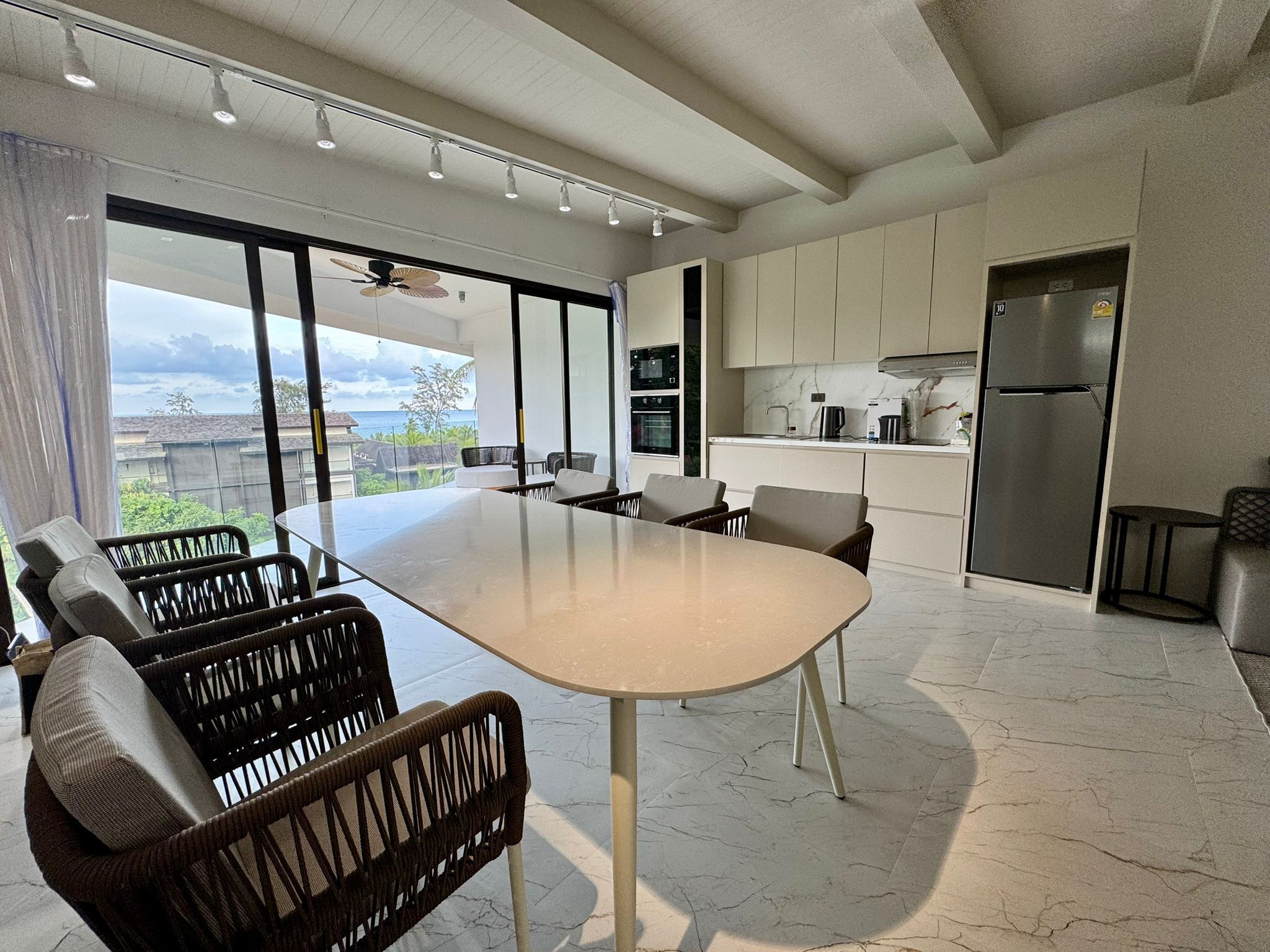 A modern kitchen with a large island, built-in appliances, and a view of the ocean.