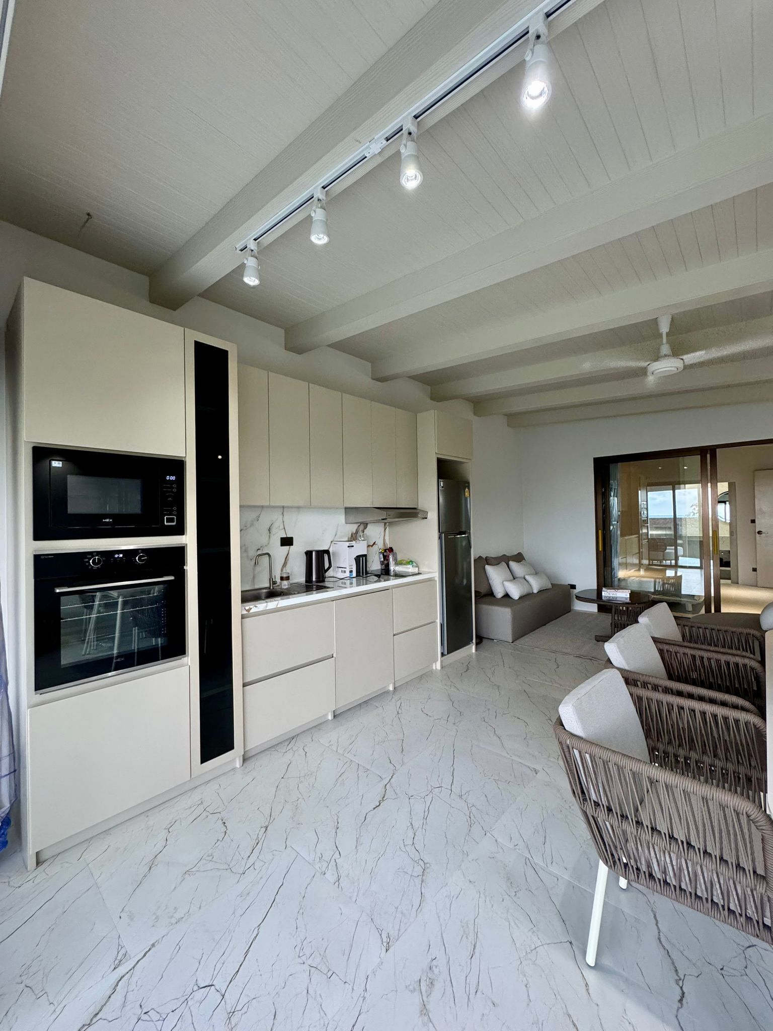 Una cocina moderna con electrodomésticos integrados, un comedor con sofá y vistas al exterior.