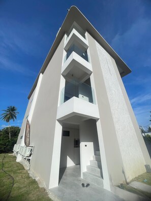 A modern building with a flat roof, large windows, and a staircase leading to the entrance. - Beachside Residence (Koh Samui)