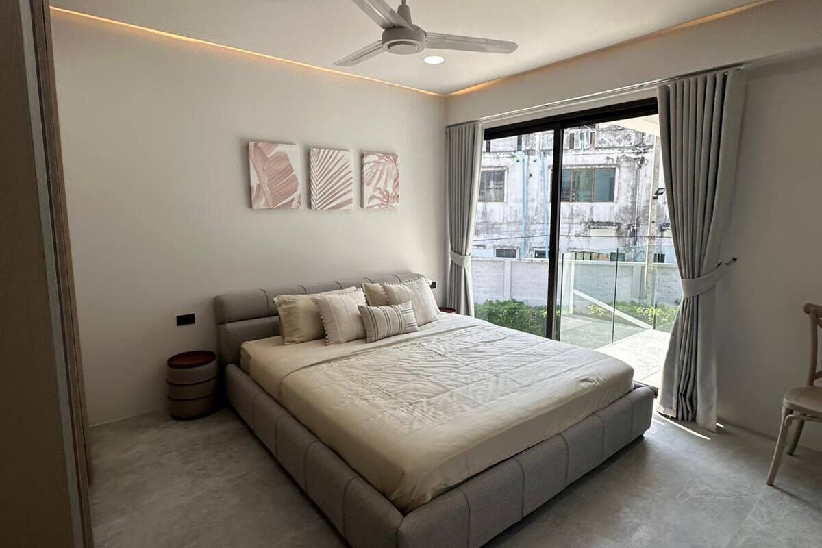 Un dormitorio moderno con una cama grande, ventilador de techo y vistas a la ciudad desde la ventana.
