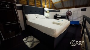 A bedroom with a bed, bedside table, lamp, and a fan. - Cozy Cabin • 5 mins from Cave Tubing & Zipline (Frank's Eddy)