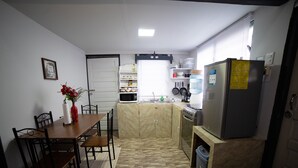 A compact kitchen with a dining table, chairs, a refrigerator, and a microwave. - Cozy Cabin • 5 mins from Cave Tubing & Zipline (Frank's Eddy)