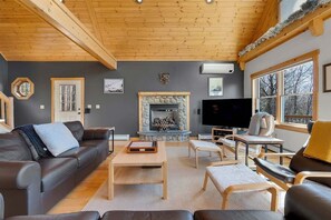 A cozy living room with a fireplace, leather furniture, and a television. - Snow Cap w/ Hot Tub and Fireplace! (Bethel)