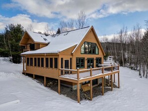 A wooden cabin with a balcony, surrounded by snow. - Snow Cap w/ Hot Tub and Fireplace! (Bethel)
