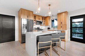 A modern kitchen with wooden cabinets, stainless steel appliances, and a central island with bar stools.