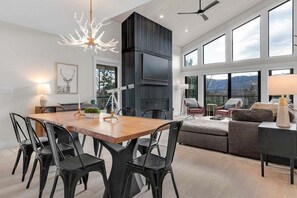 A modern living space with a dining area, a fireplace, and large windows offering a mountain view.