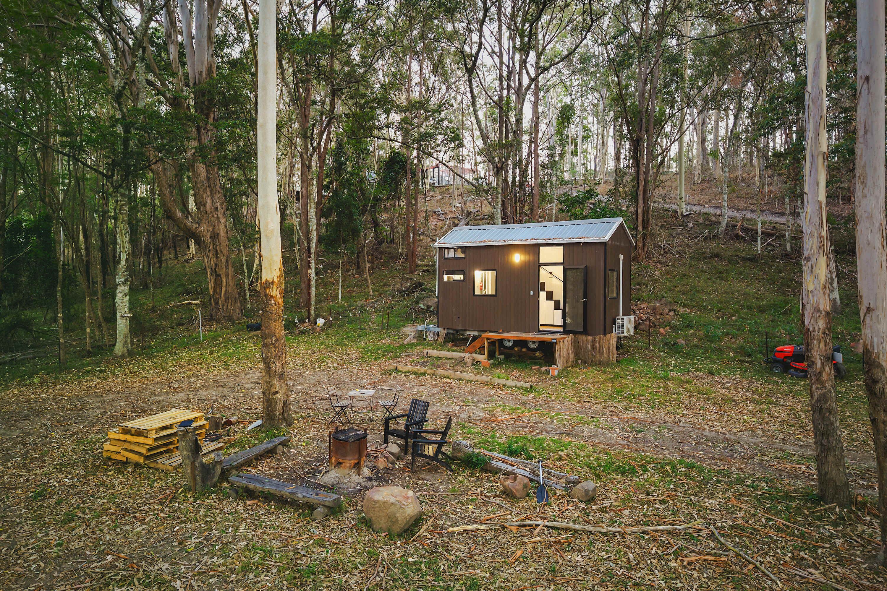 Una cabaña pequeña en un bosque con vistas despejadas a los árboles circundantes y una zona de fogata.