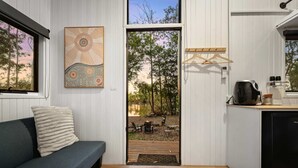 Ein modernes Interieur mit einer Couch, einer Tür zu einer Terrassenanlage und einer Küchenzeile mit Kaffeemaschine.