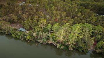 Vue aérienne d’une zone boisée avec un petit quai qui s’avance dans un plan d’eau.