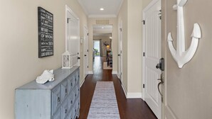 A hallway with a white anchor decoration, a sign with inspirational quotes, and a light blue dresser. - Pond-Side Retreat | Pool | Bikes | Beach Chairs & Wagon | Patio w/ Grill | Clean & Bright End Unit (St. Simons Island)