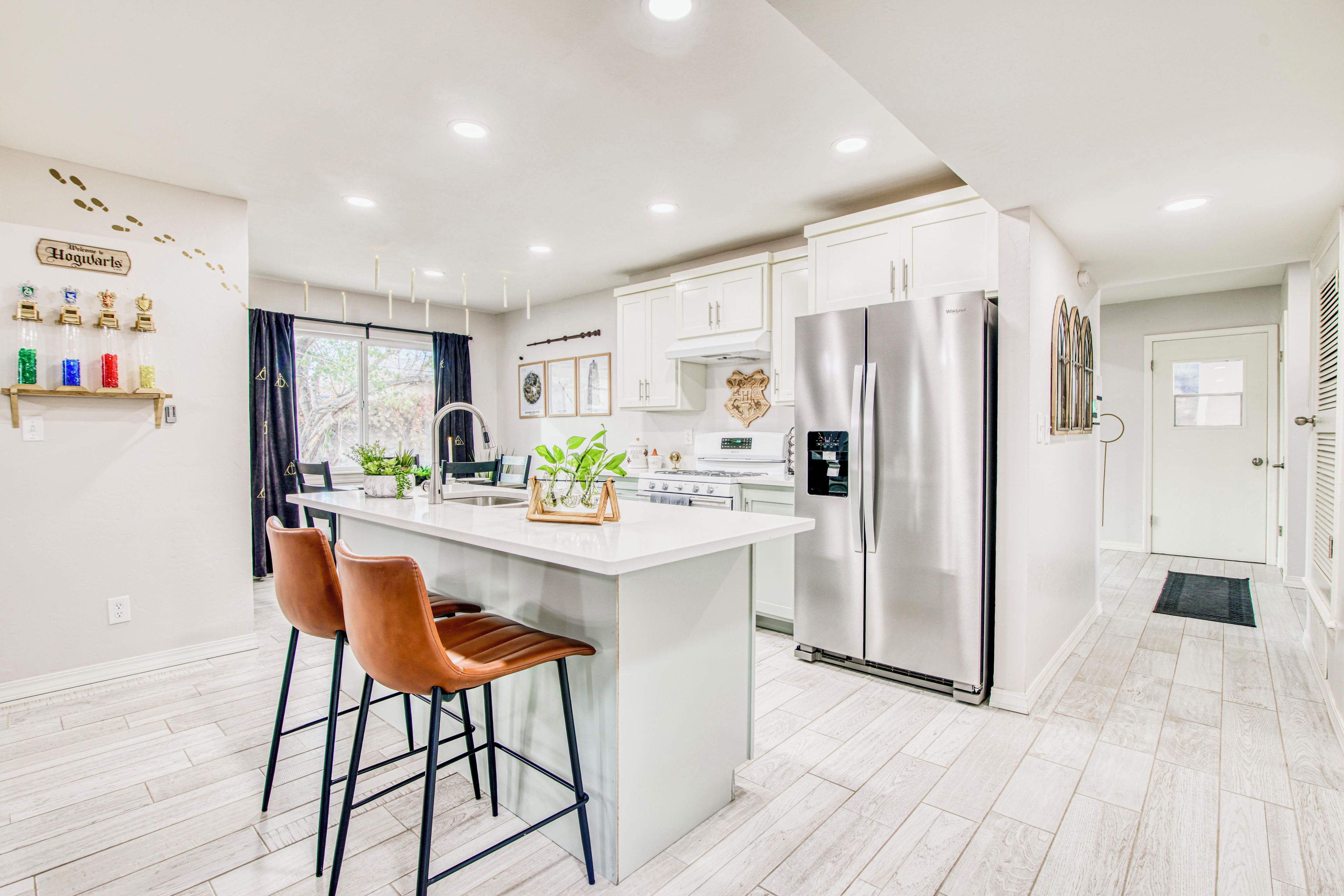 Una cocina moderna con una isla central, electrodomésticos de acero inoxidable y una decoración en tonos blancos.