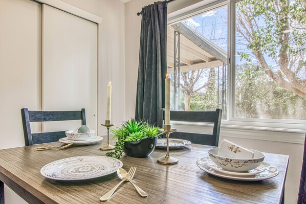 Une table à manger dressée avec des assiettes, des couverts, des bougies et une plante en pot.