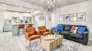 A modern living room with a dark leather sofa, two brown armchairs, a wooden coffee table, and a blue patterned rug. - 3 bedroom 2 bath Magical home (El Paso)