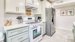 A modern kitchen with white cabinets, stainless steel appliances, and a wooden backsplash. - 3 bedroom 2 bath Magical home (El Paso)