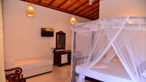 A bedroom with a canopy bed, a wooden desk, a chair, and a television on the wall. - Surf Villa (Hikkaduwa)