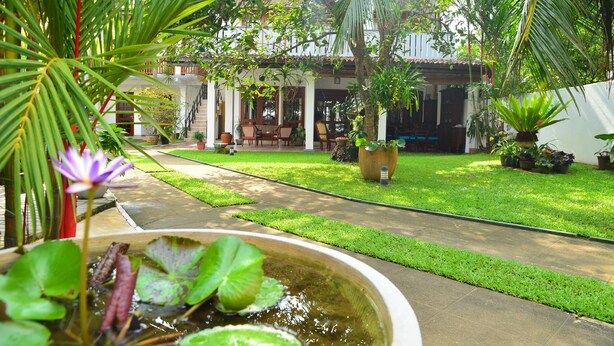 A courtyard with a water feature, potted plants, and a seating area. - Surf Villa (Hikkaduwa)