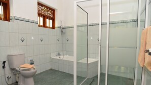 A bathroom with a toilet, sink, and glass-enclosed shower. - Surf Villa (Hikkaduwa)