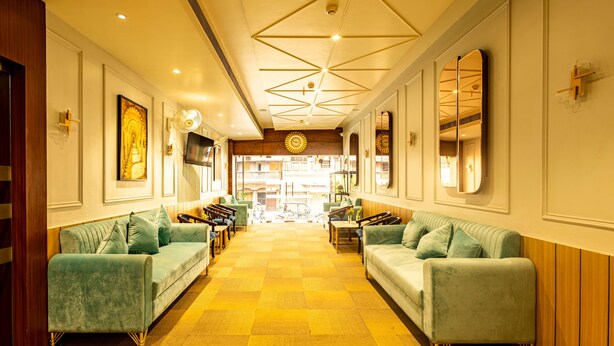 Eine Hotelhalle mit Schachbrettmuster-Boden, zwei gegenüberliegende Sofas und einer Decke mit geometrischen Mustern.
