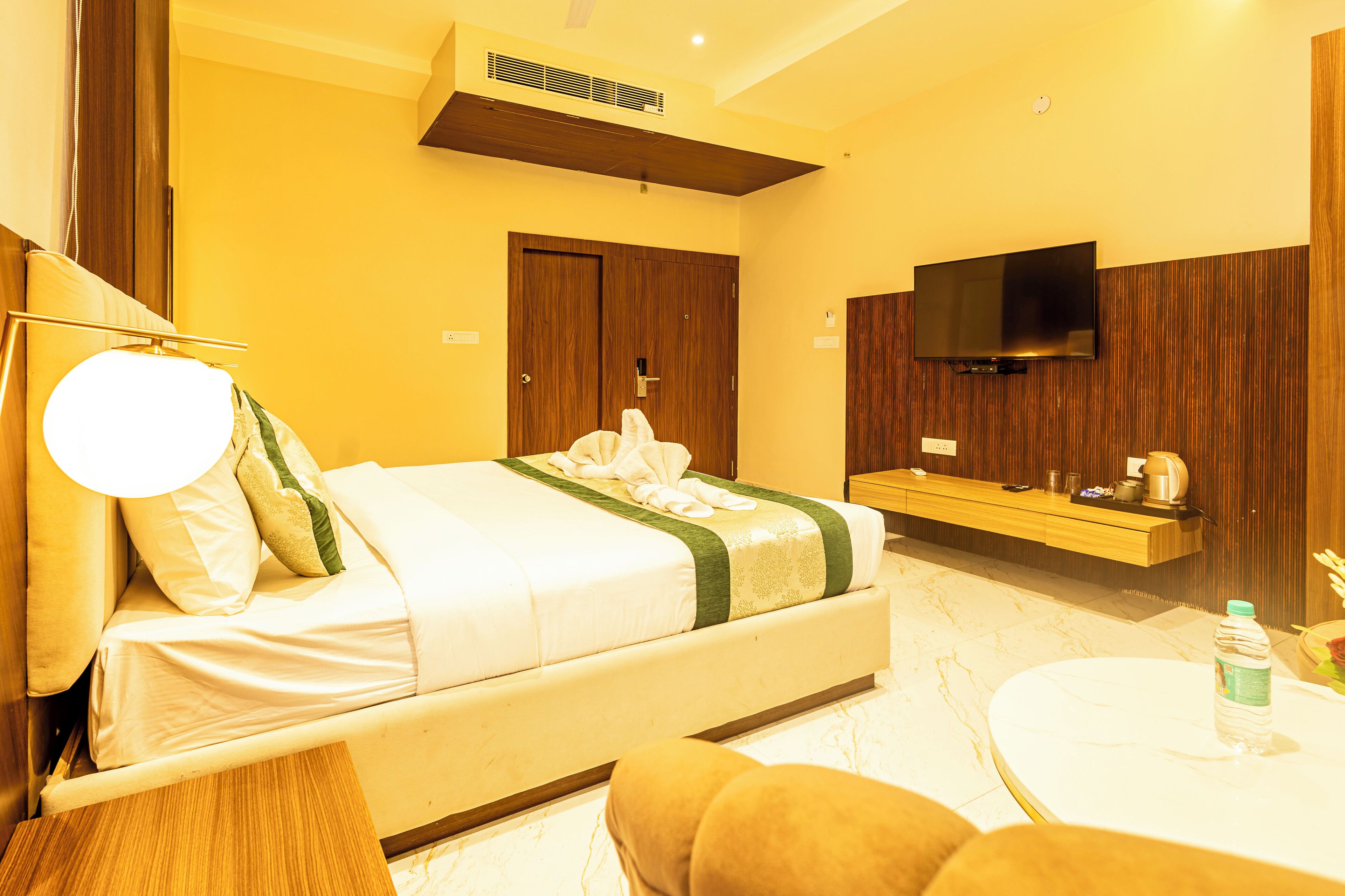 A hotel room with a bed, a TV, a bedside table, and a small round table.