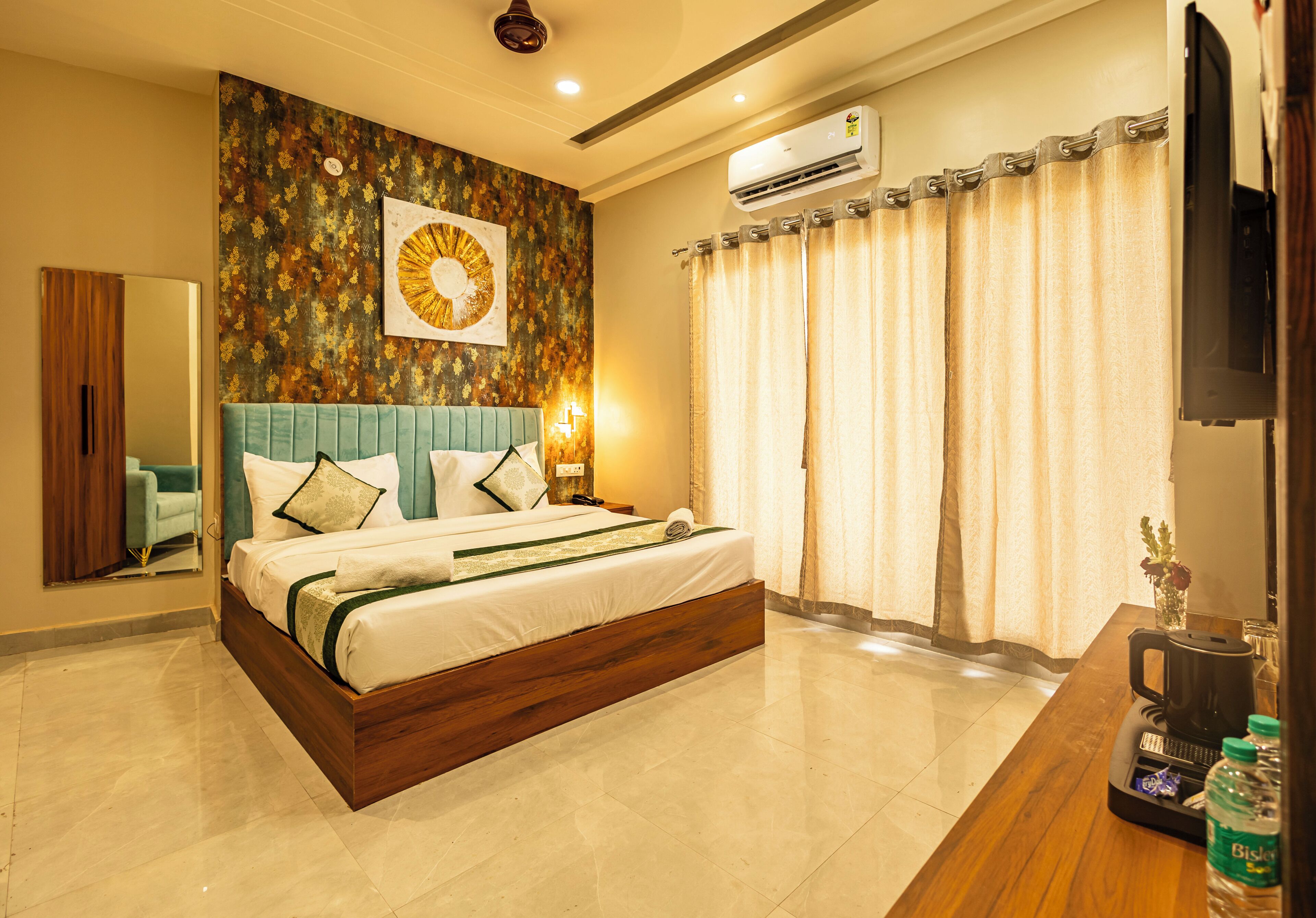 A modern hotel room with a large bed, a flat-screen TV, an air conditioning unit, and a coffee maker on the side table.