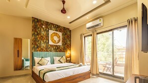 Ein geräumiges Schlafzimmer mit einem großen Bett, einem Deckenventilator, einer Klimaanlage und Blick ins Freie durch eine Glastür.