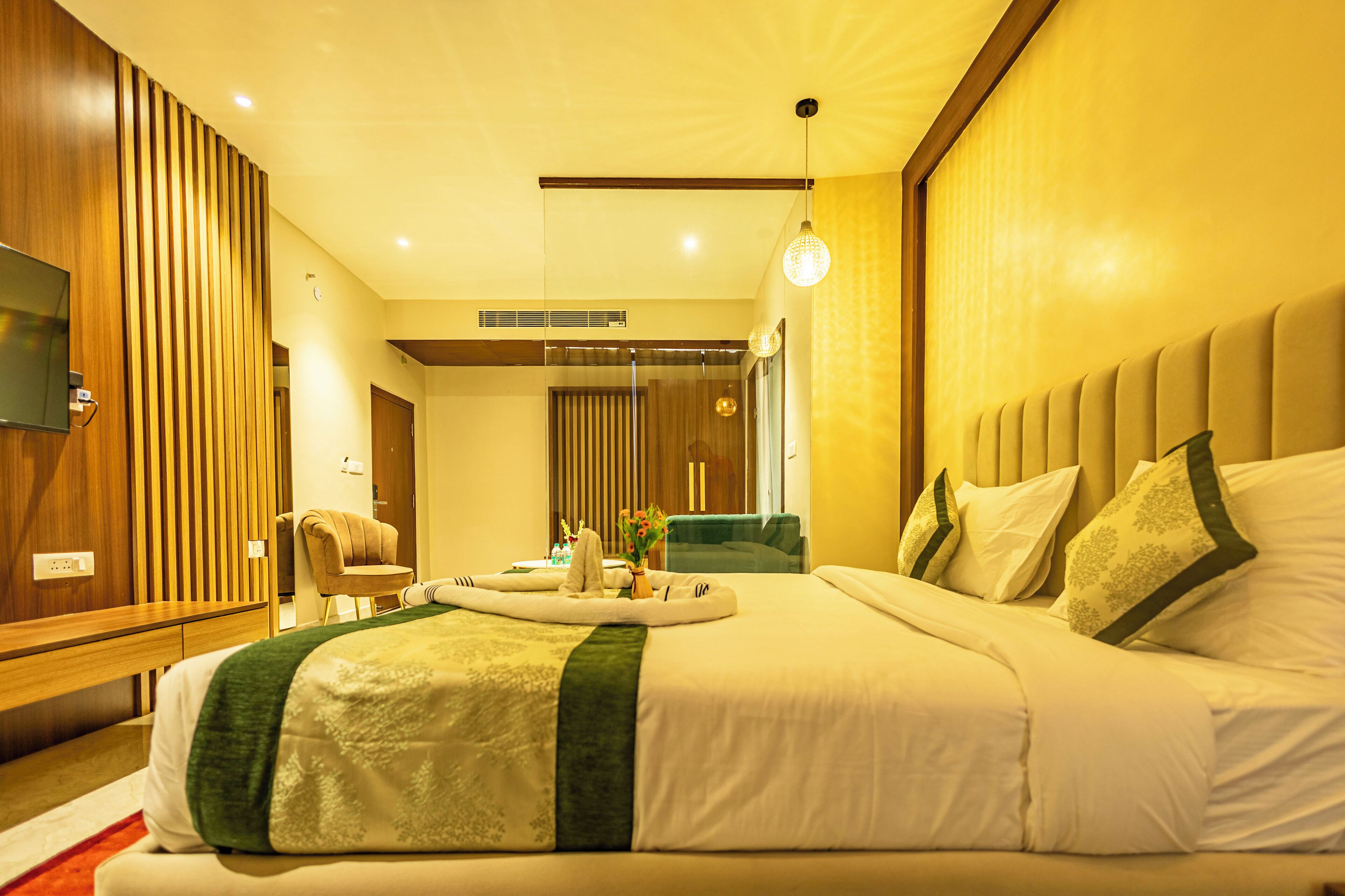 Una camera d'albergo moderna con un letto grande, una televisione a schermo piatto, un'area salotto con una poltrona e uno specchio.