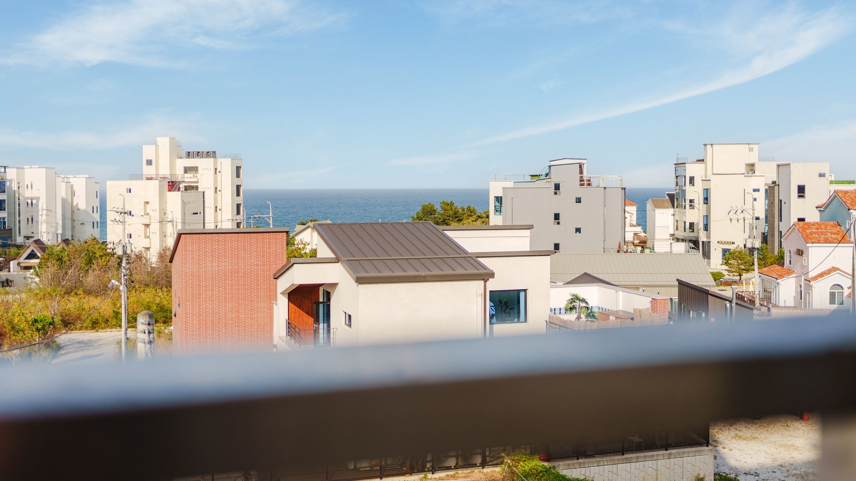 A residential area with modern buildings, a clear view of the sea, and a balcony with a view.