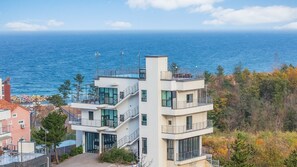 A multi-story building with balconies, a staircase, and a view of the sea. - Gangreung top spa Pension (Gangneung)