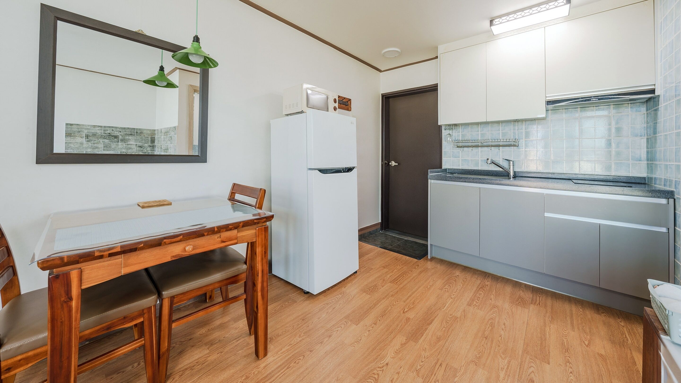Une cuisine compacte équipée d’un réfrigérateur, d’un évier et d’un coin repas avec une table et des chaises.