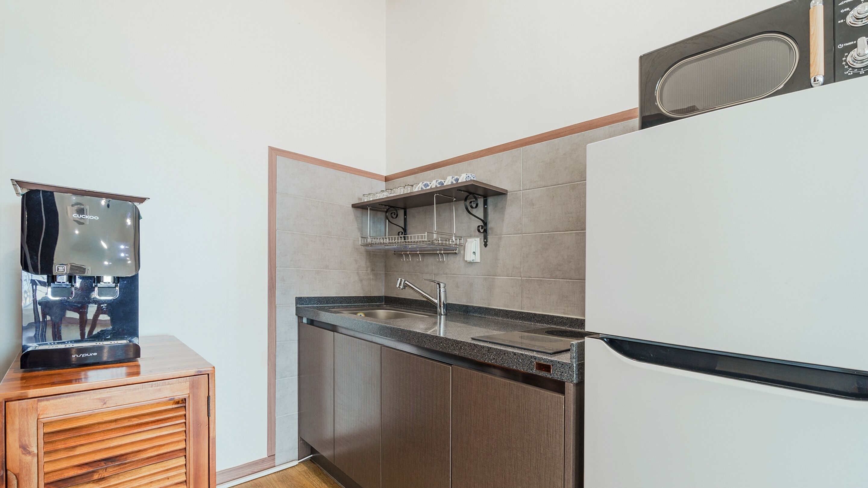 Een kleine keuken met een koffiezetapparaat, een spoelbak en een magnetron.