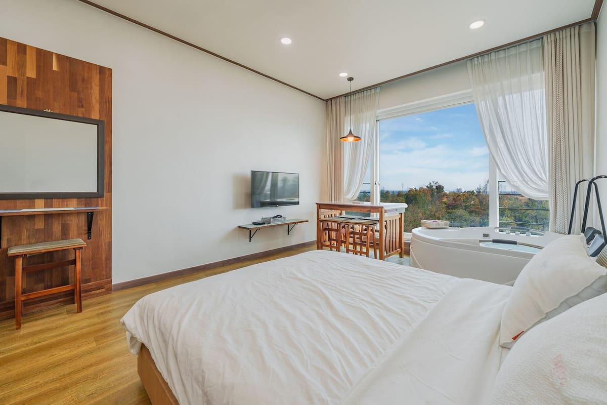 Een moderne hotelkamer met een groot bed, een bureau met stoel, een televisie en een whirlpool.