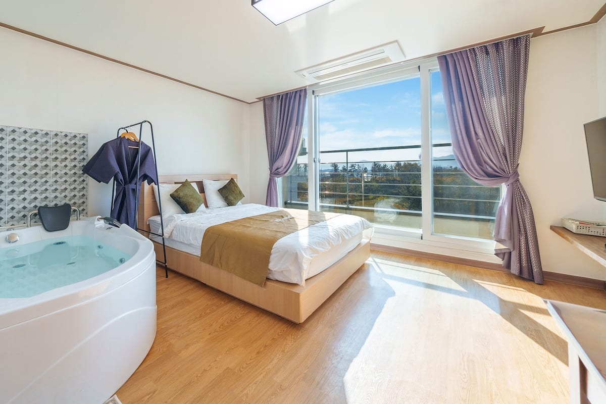 Een moderne slaapkamer met een groot bed, een ingebouwd whirlpoolbad en een balkon met uitzicht.