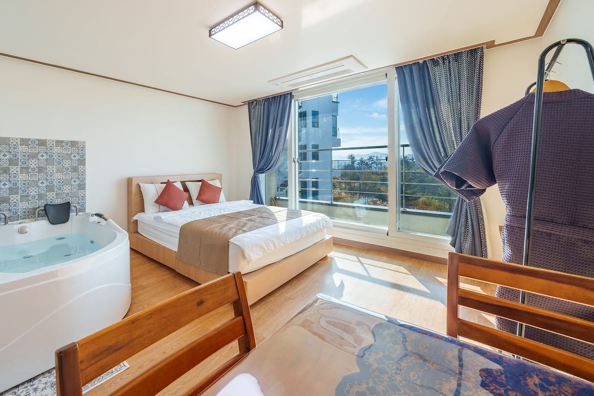 Een moderne hotelkamer met een groot bed, een badkuip en een balkon met uitzicht.