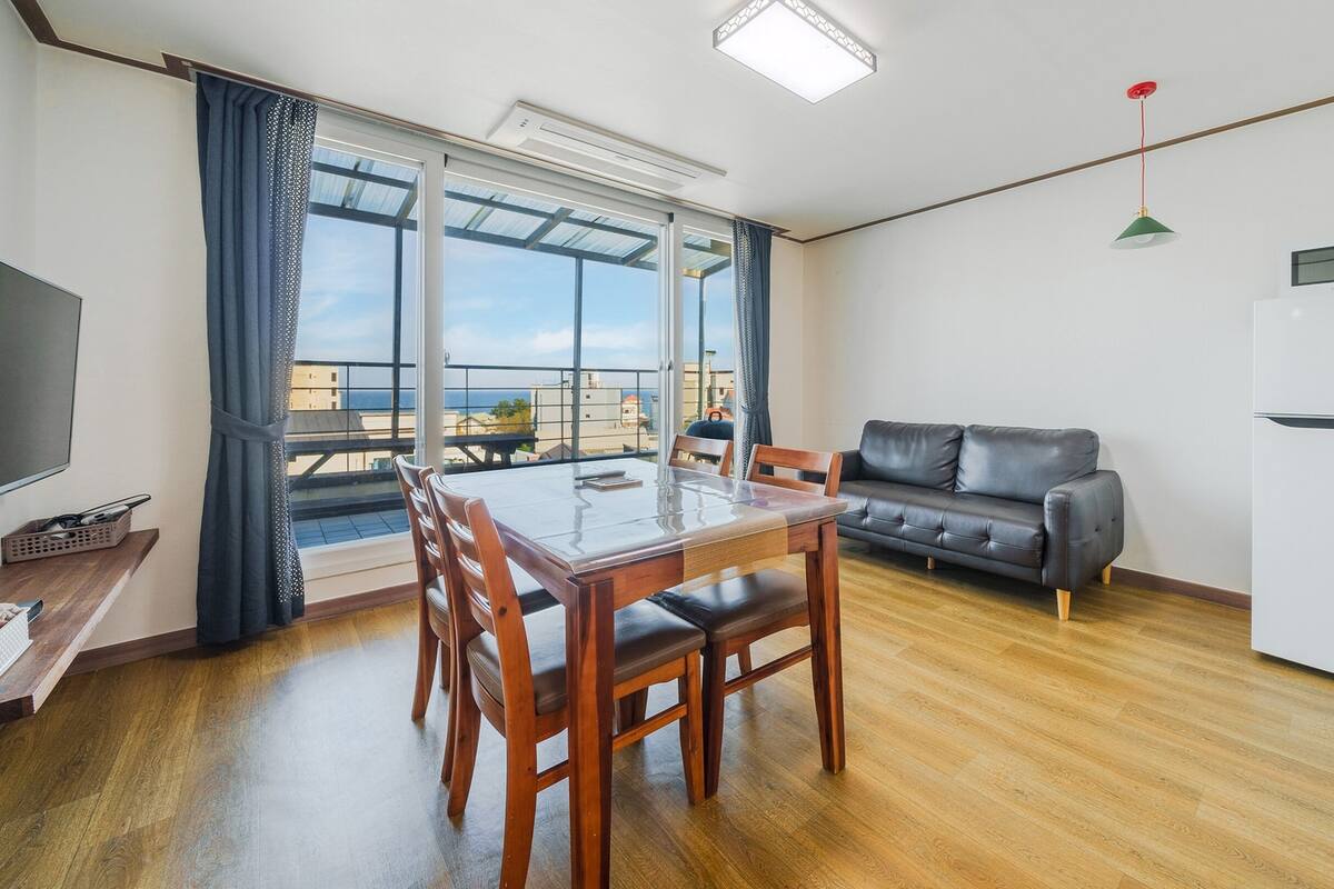Een moderne woonkamer met een eettafel, bank en een groot raam met uitzicht op de stad.