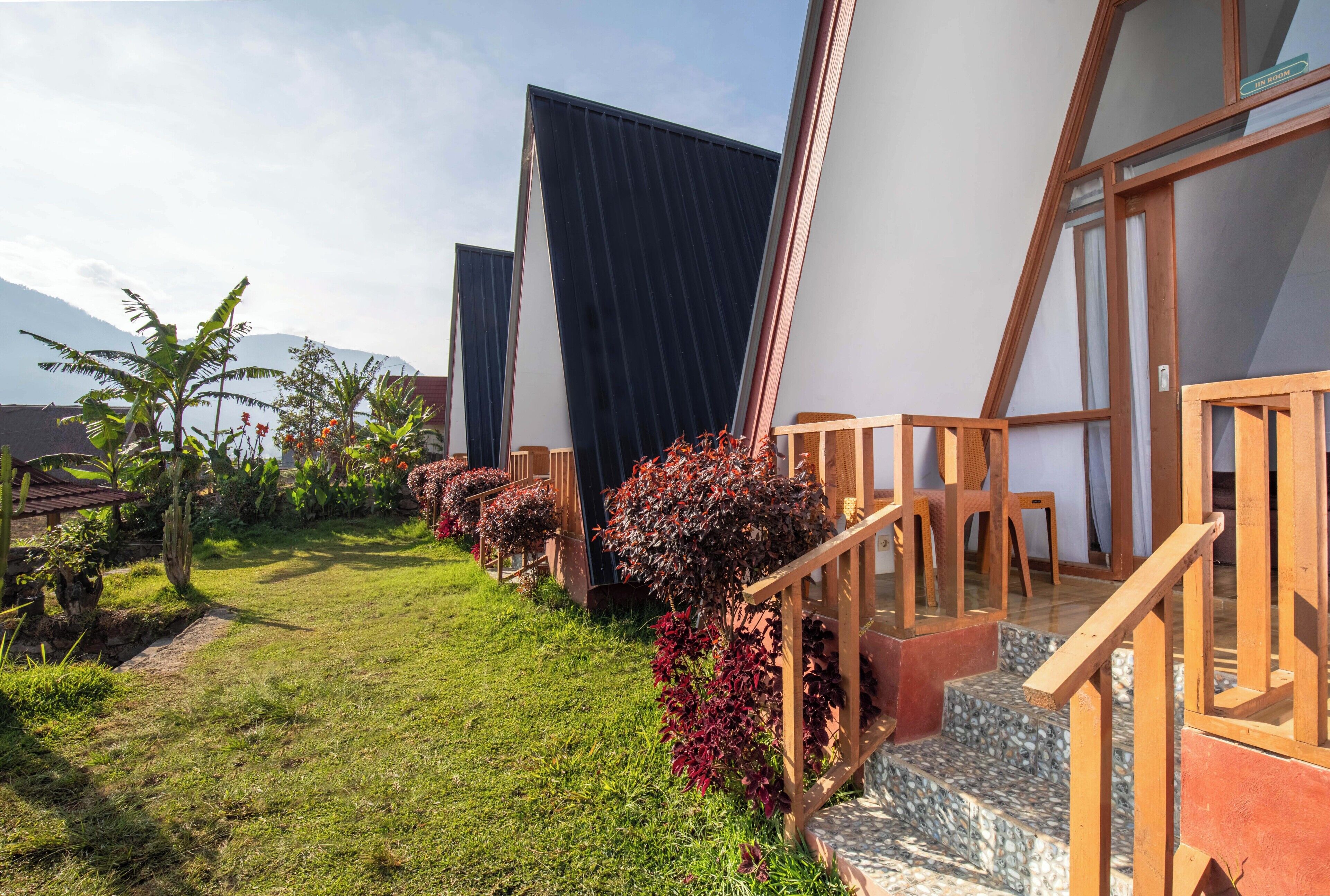A modern building with a garden, wooden steps, and a clear sky.