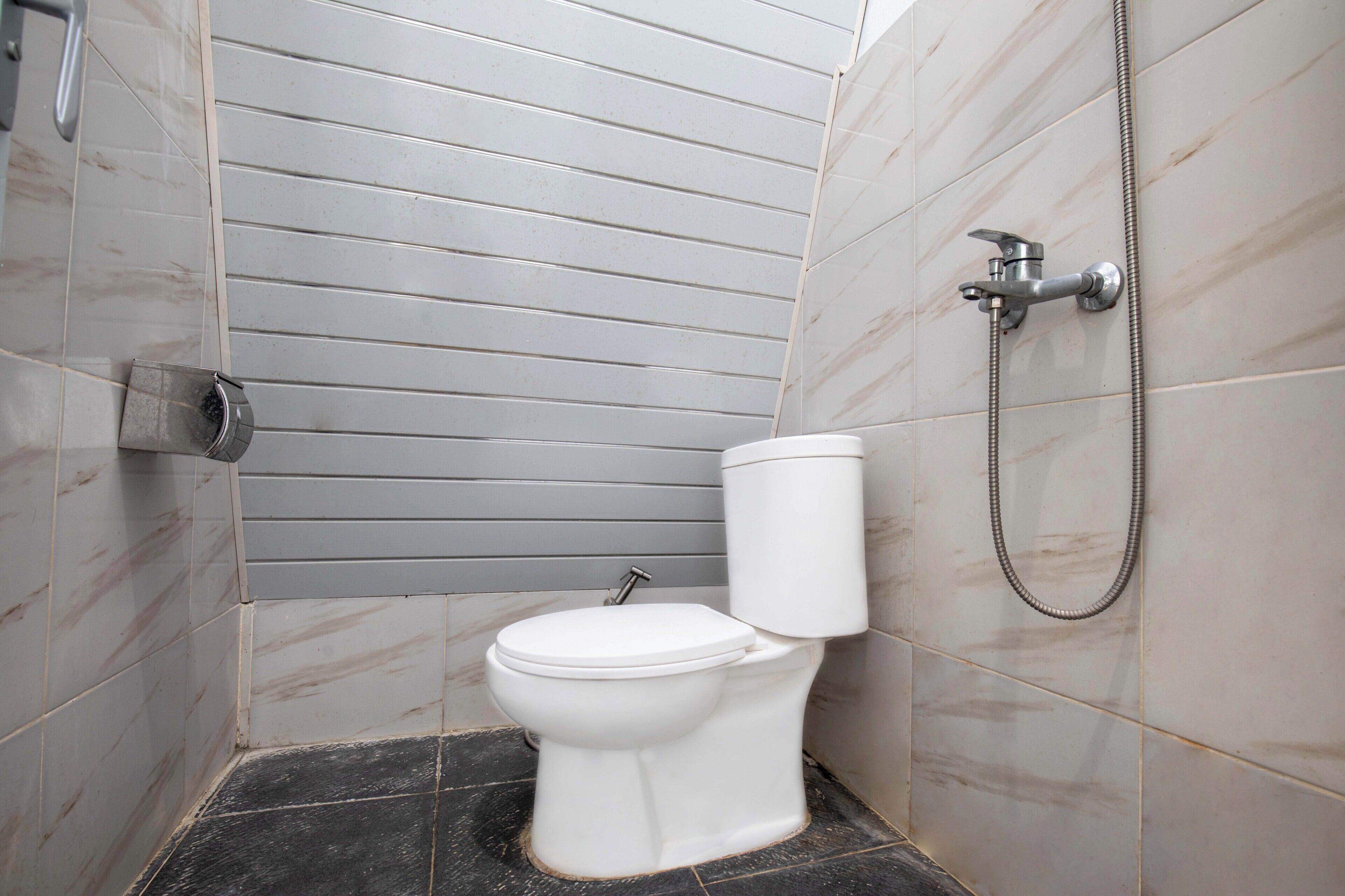 Un baño con inodoro, ducha y secamanos de pared.