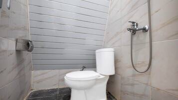 Un baño con inodoro, ducha y secamanos de pared.