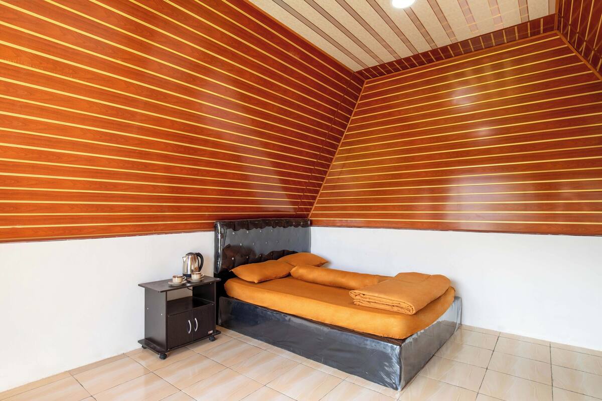 Une chambre à coucher avec un lit, une table de chevet et une petite armoire.